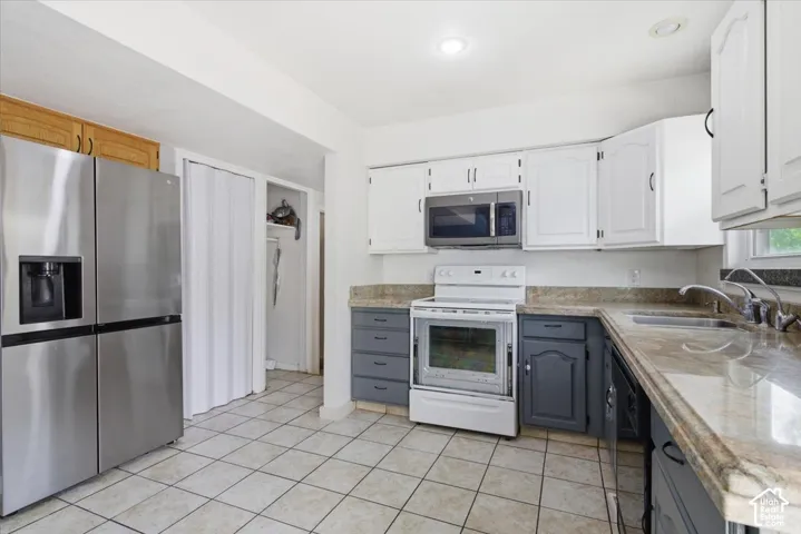 Two tone kitchen featuring two tone cabinetry, stainless steel appliances, and light tile patterned floors