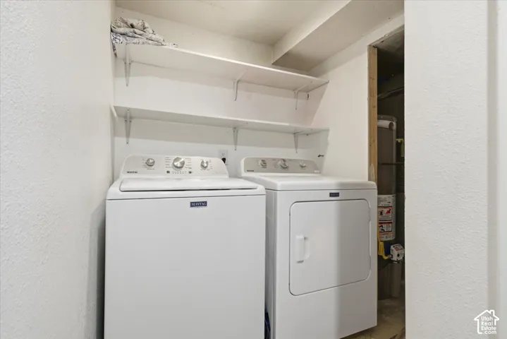 Laundry area featuring a textured wall, independent washer and dryer, and gas water heater