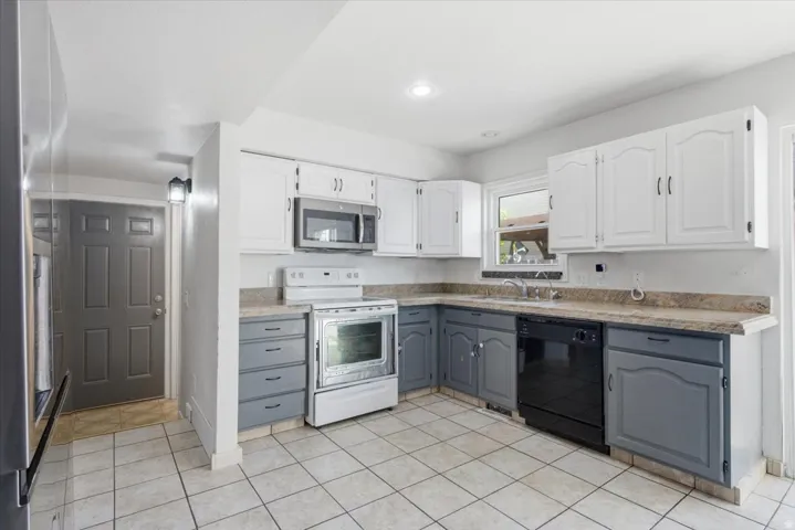 Kitchen featuring dual tone cabinets, stainless steel appliances, and light tile patterned floors