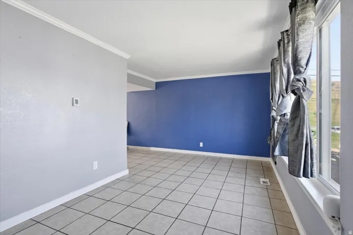 Empty room with ornamental molding and light tile patterned floors