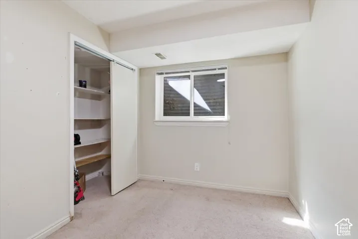 Unfurnished bedroom with light colored carpet and a closet