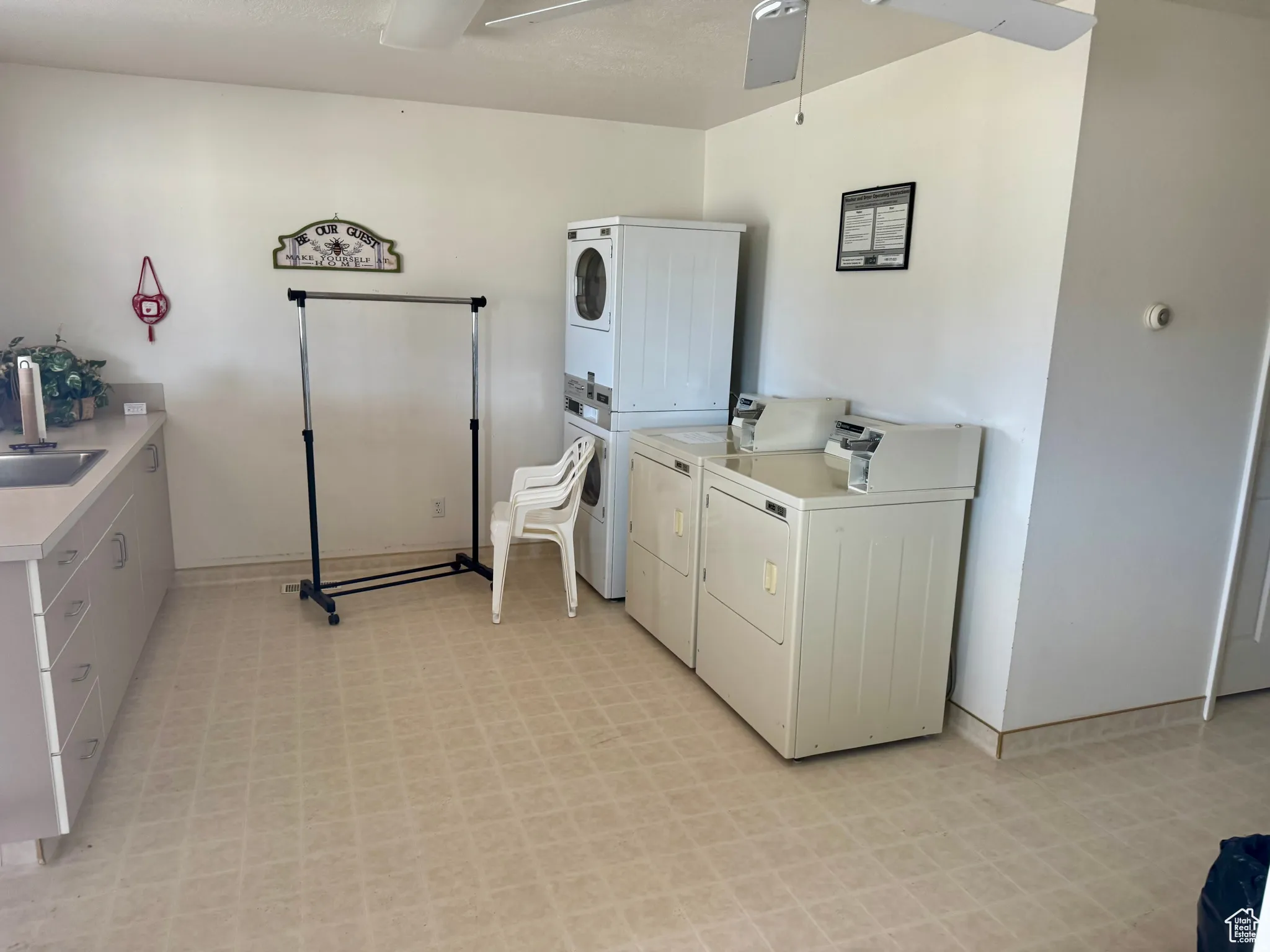 Communal laundry room featuring light floors, ceiling fan, and stacked washer / drying machine