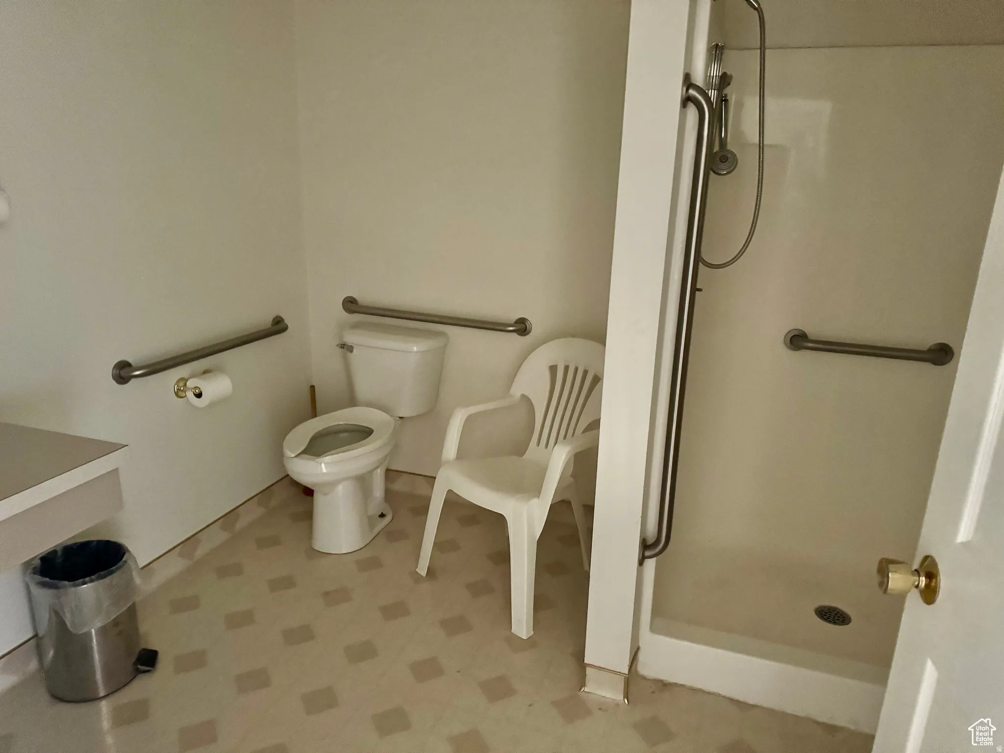 Bathroom with light flooring and a shower stall