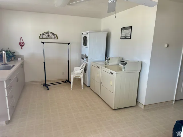 Communal laundry room featuring light floors, ceiling fan, and stacked washer / drying machine