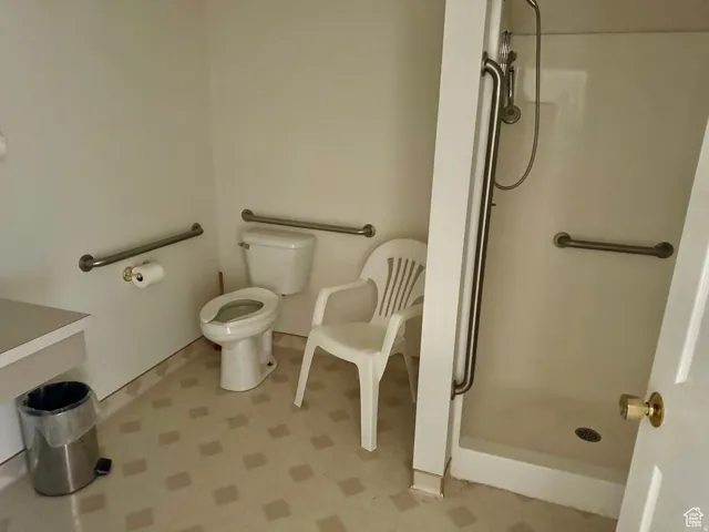 Bathroom with light flooring and a shower stall