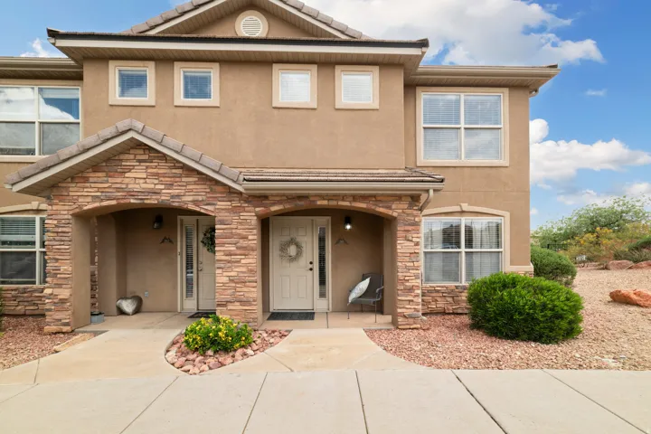 Traditional-style home with stone siding, stucco siding, and covered porch