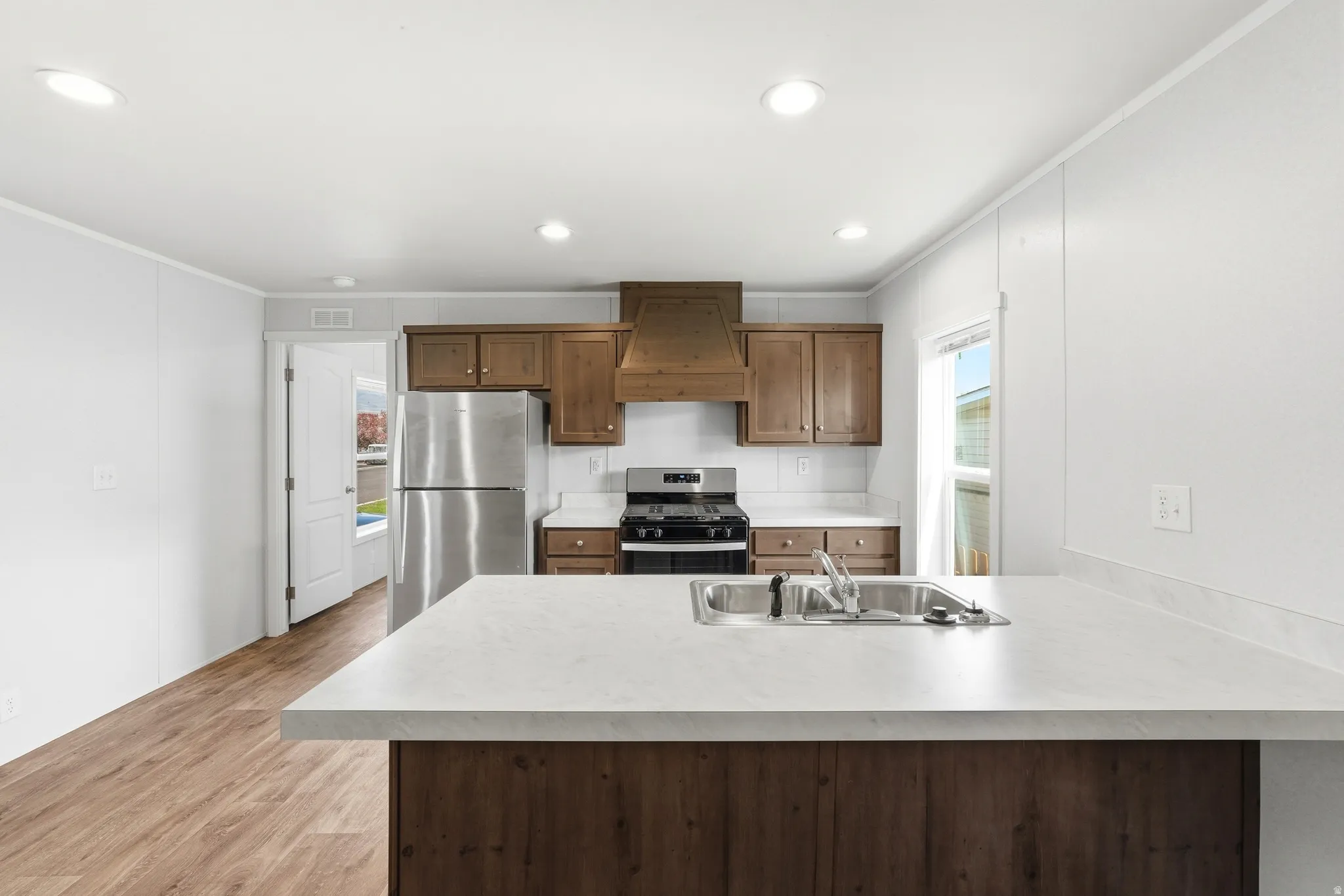 Kitchen with stainless steel appliances, a peninsula, ornamental molding, recessed lighting, and light wood-type flooring
