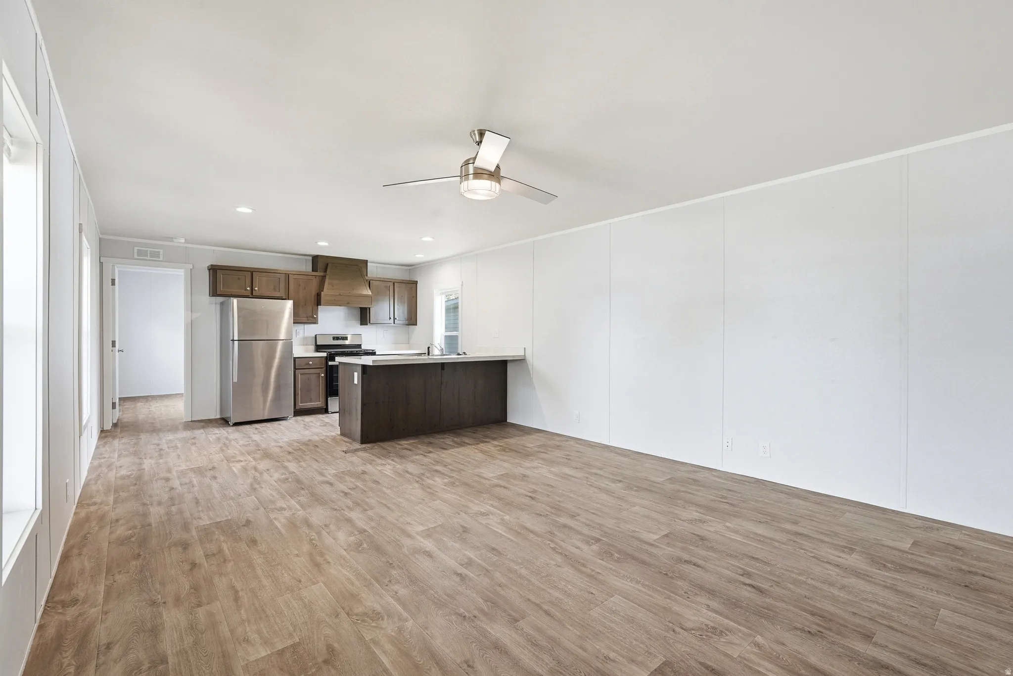 Kitchen with a peninsula, ceiling fan, recessed lighting, stainless steel appliances, and light countertops