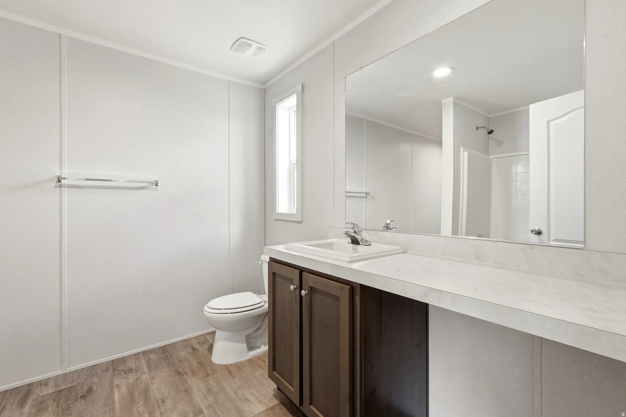 Bathroom with vanity, light wood-style flooring, a shower stall, and ornamental molding