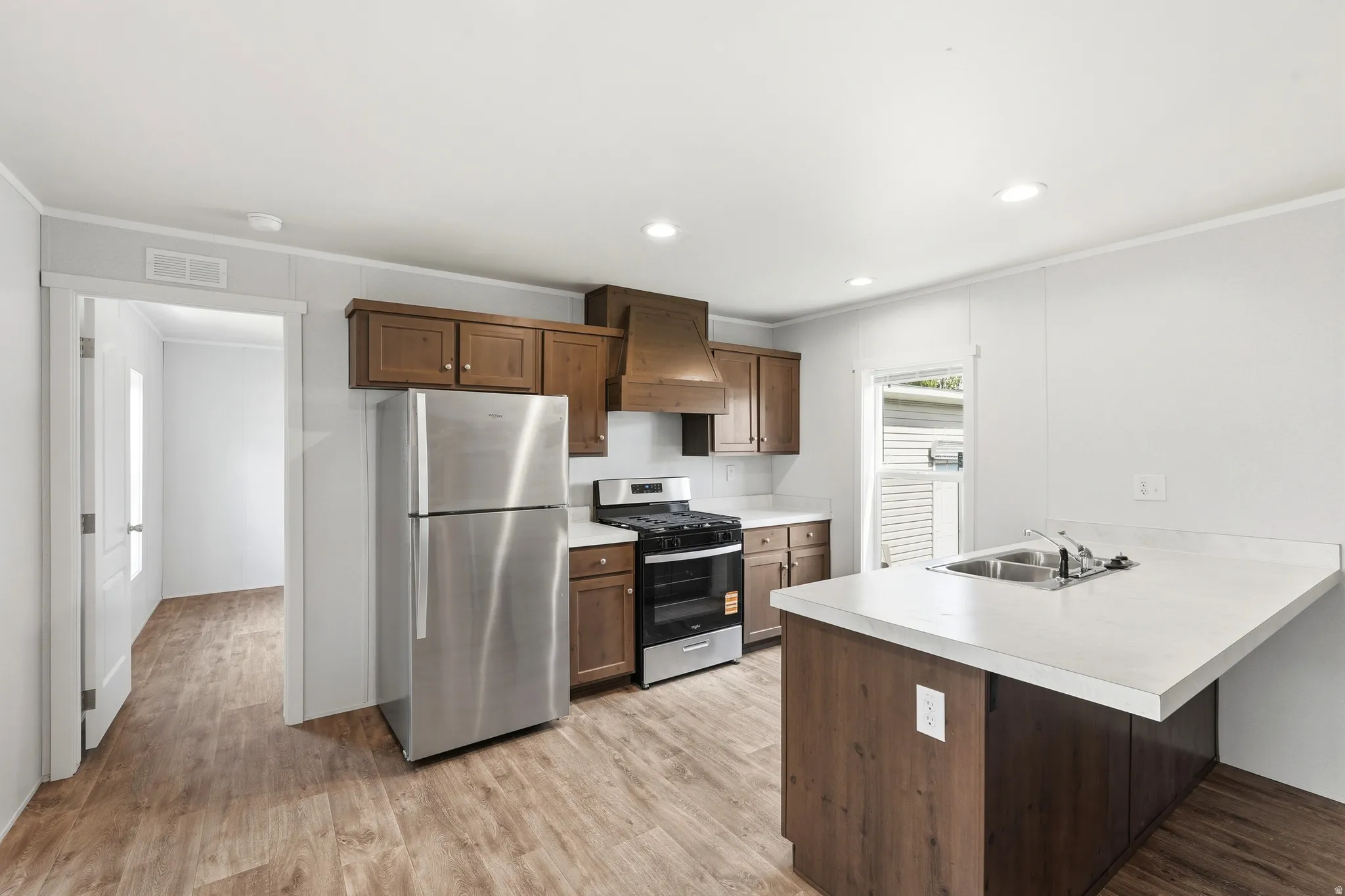 Kitchen with a peninsula, stainless steel appliances, light countertops, a breakfast bar area, and crown molding
