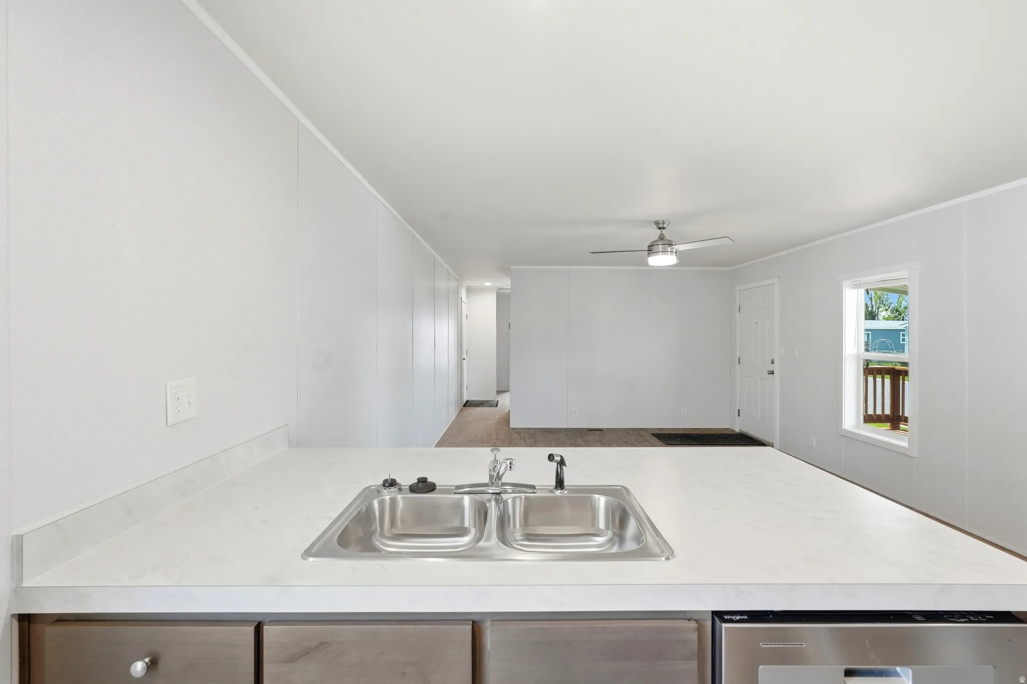 Kitchen with crown molding, light countertops, a ceiling fan, dishwasher, and a peninsula