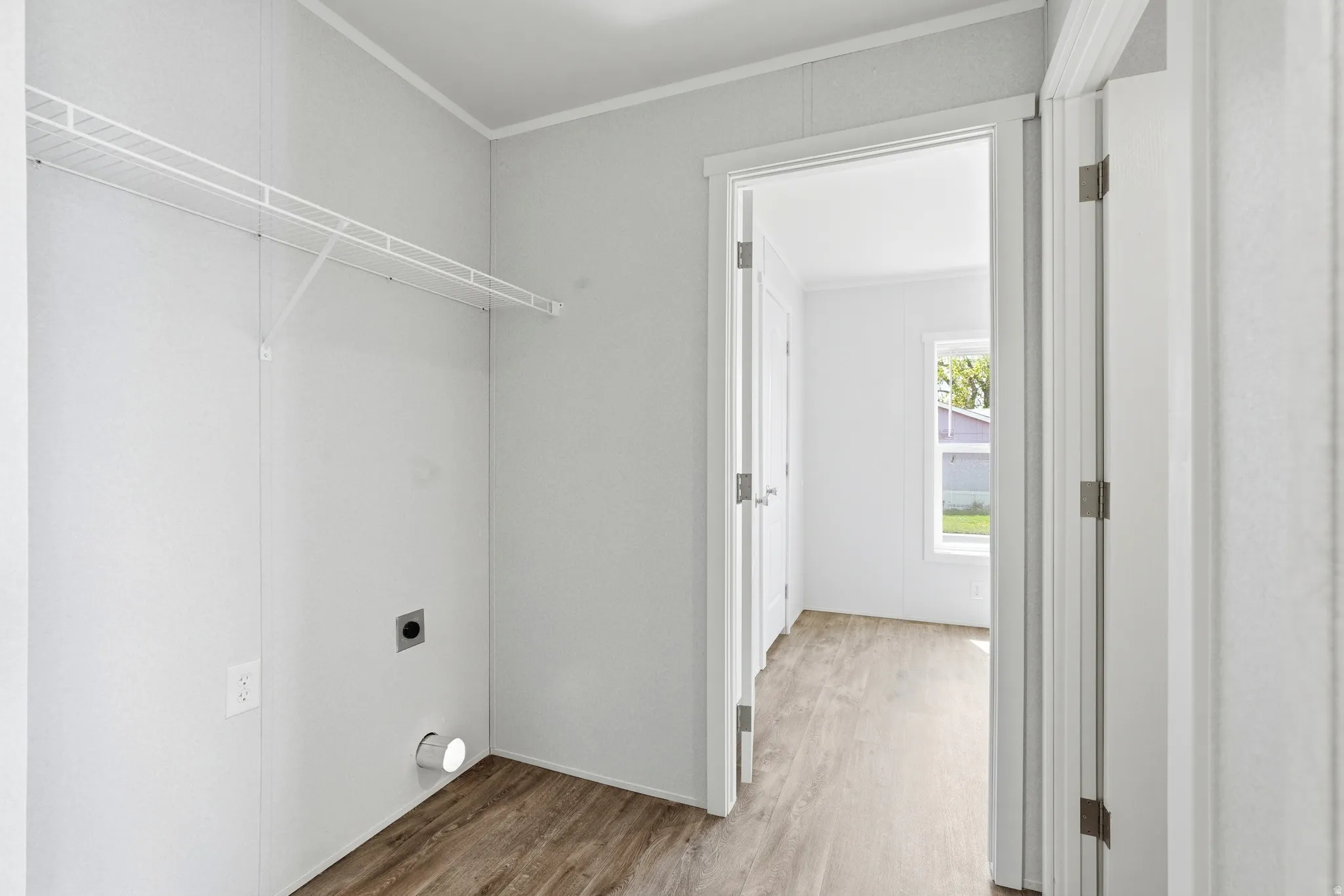 Laundry area with crown molding, light wood-style flooring, and electric dryer hookup