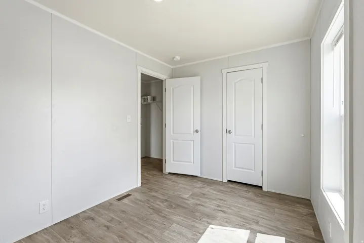 Unfurnished bedroom with light wood-style floors, crown molding, and a closet
