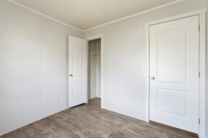 Unfurnished bedroom featuring light wood-style floors, ornamental molding, and a closet