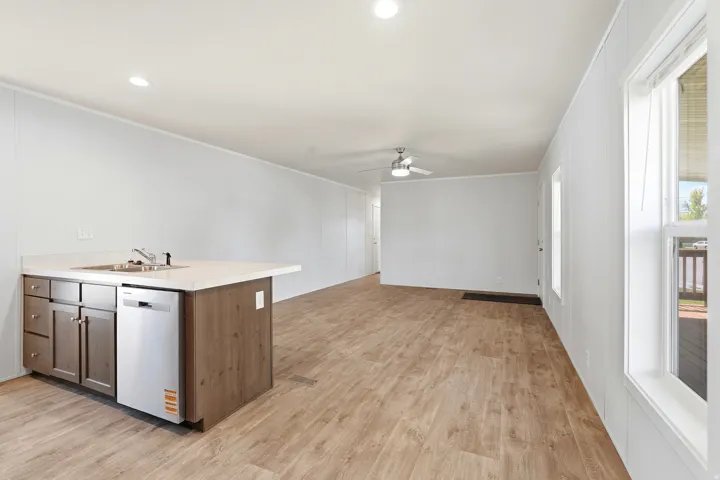 Kitchen featuring light countertops, stainless steel dishwasher, light wood-style floors, a ceiling fan, and open floor plan