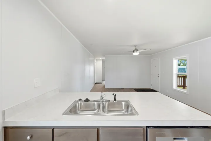 Kitchen with crown molding, light countertops, a ceiling fan, dishwasher, and a peninsula