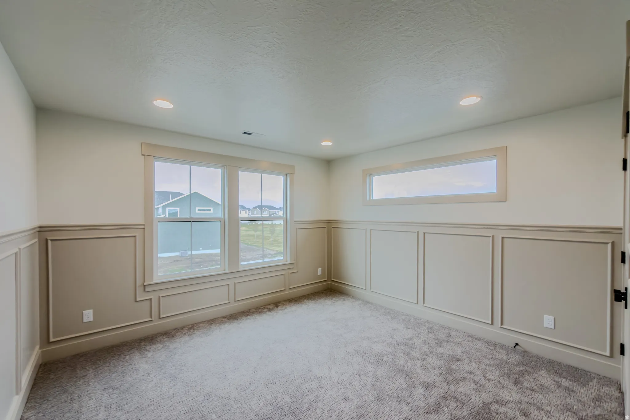 Spare room with wainscoting, a decorative wall, carpet floors, and a textured ceiling