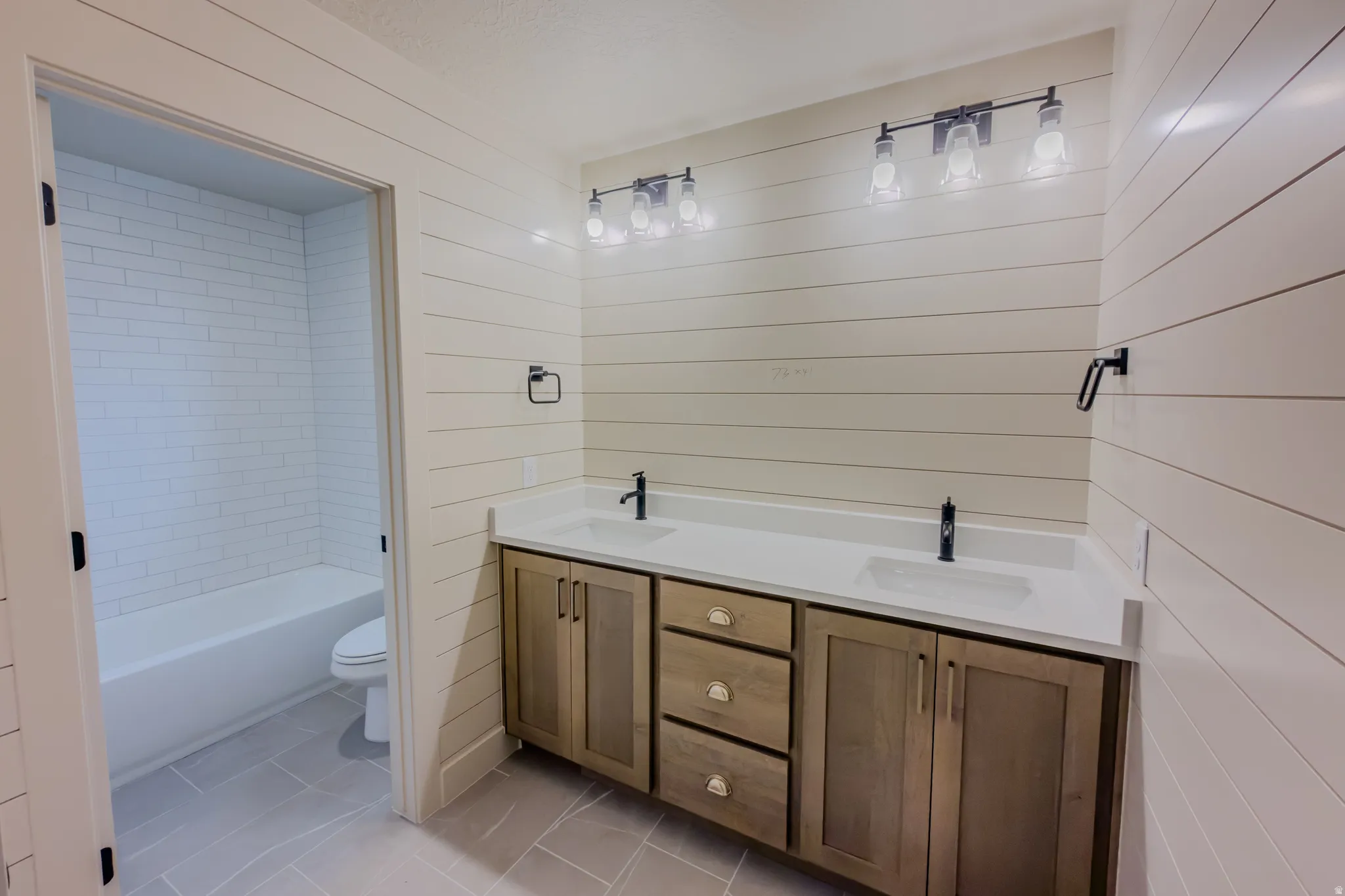 Bathroom featuring double vanity, light tile patterned floors, and wooden walls
