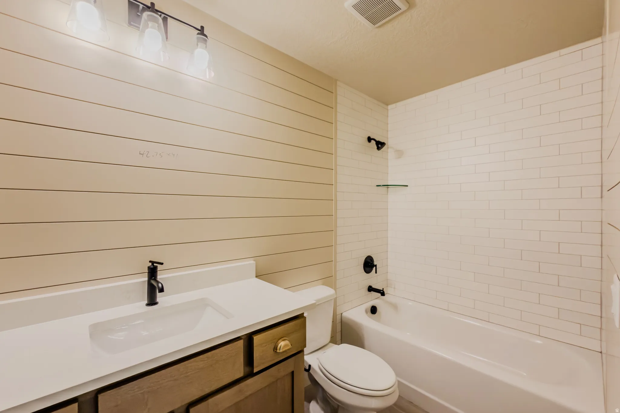 Bathroom featuring vanity, bathing tub / shower combination, and wooden walls