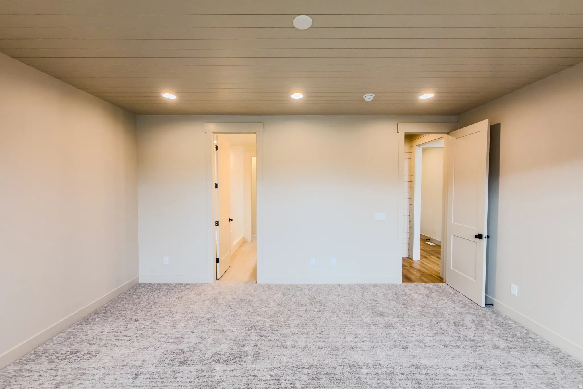 Empty room with light colored carpet, recessed lighting, and wood ceiling