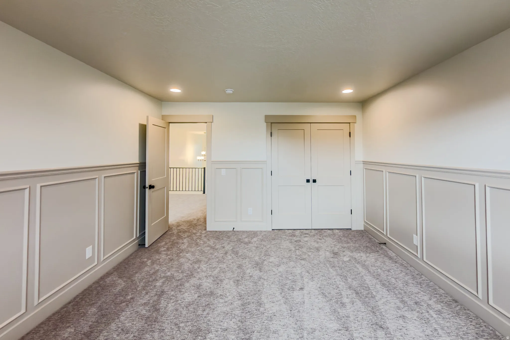 Unfurnished bedroom with wainscoting, a decorative wall, recessed lighting, a closet, and light colored carpet