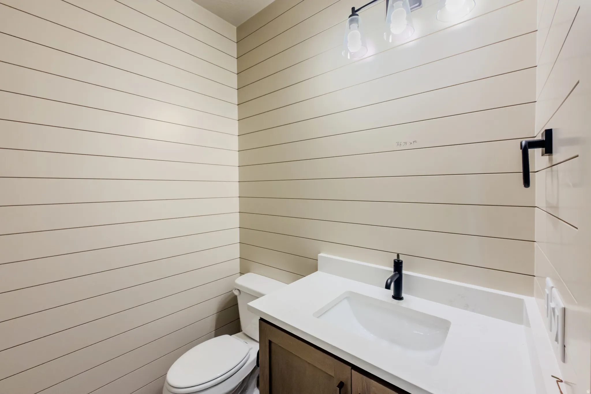 Half bath with vanity and wooden walls