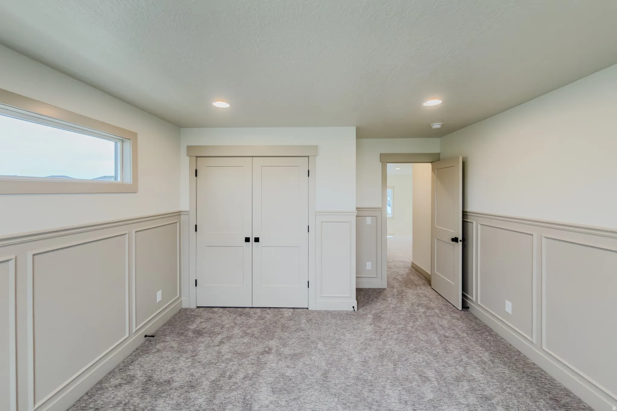 Unfurnished bedroom featuring a decorative wall, a wainscoted wall, a closet, recessed lighting, and light carpet