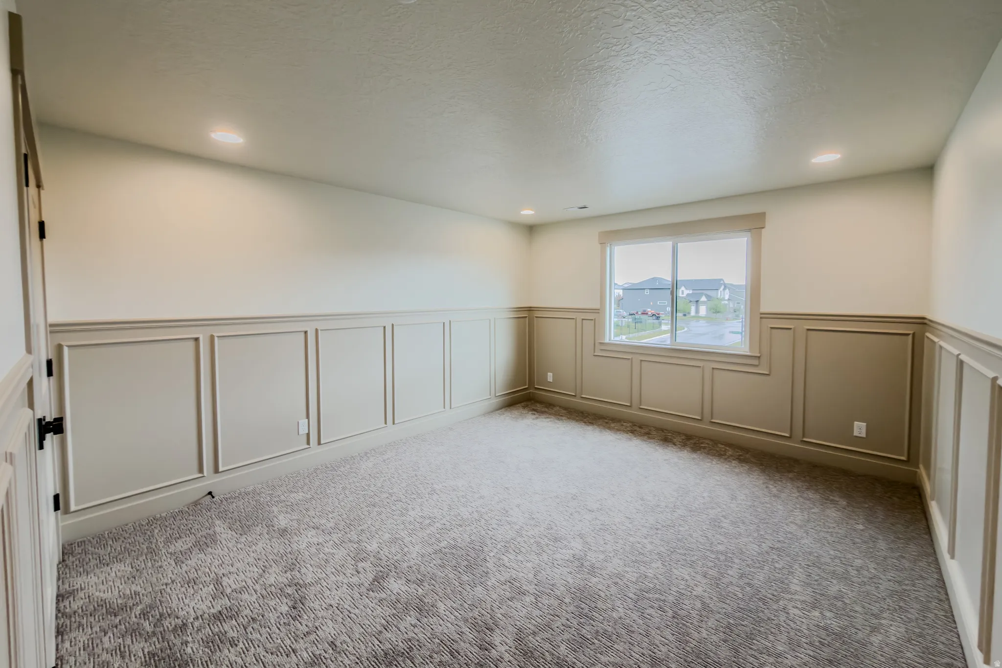 Carpeted empty room featuring wainscoting, a decorative wall, a textured ceiling, and recessed lighting