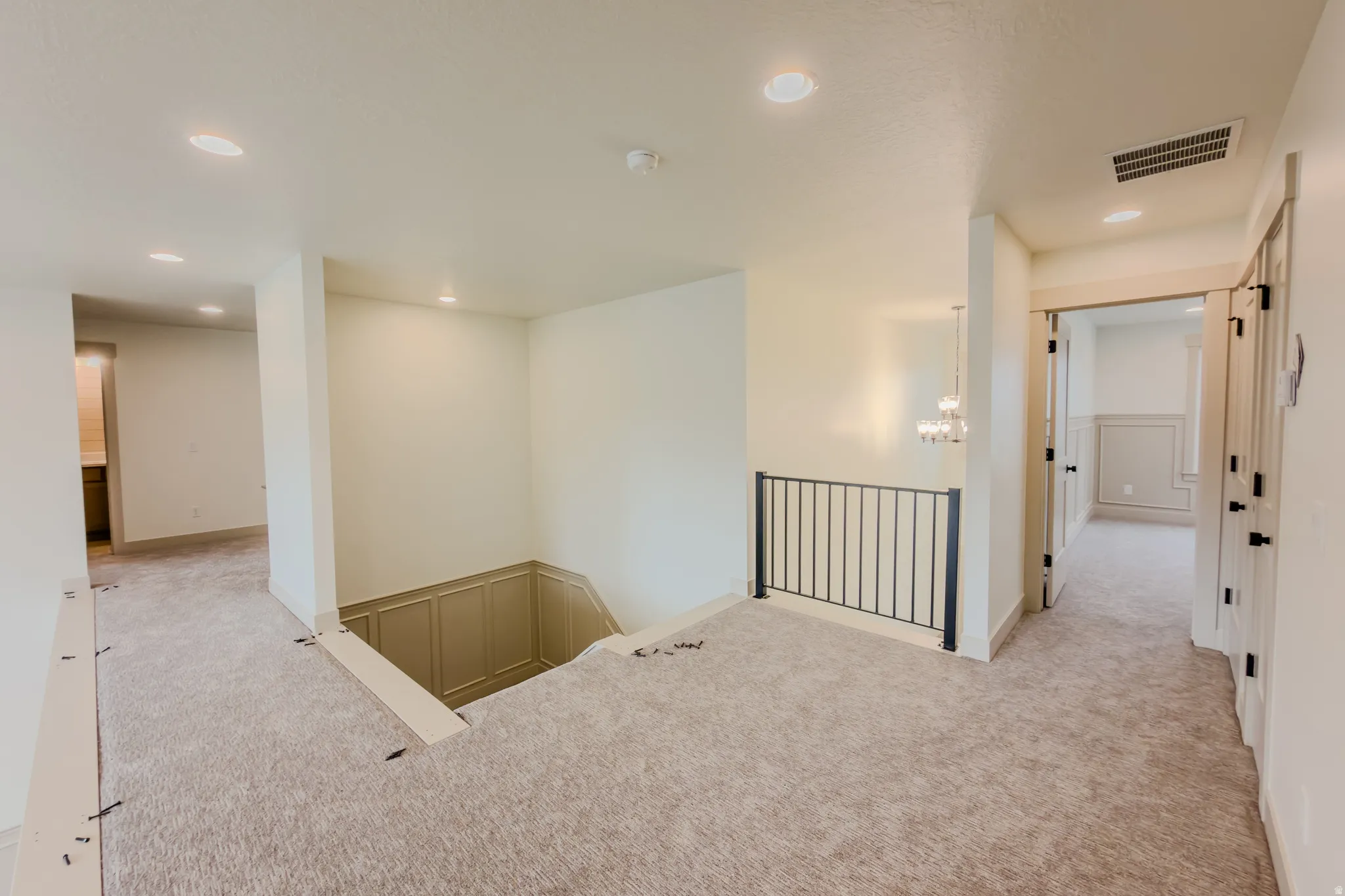 Corridor featuring light carpet, recessed lighting, a decorative wall, and an upstairs landing
