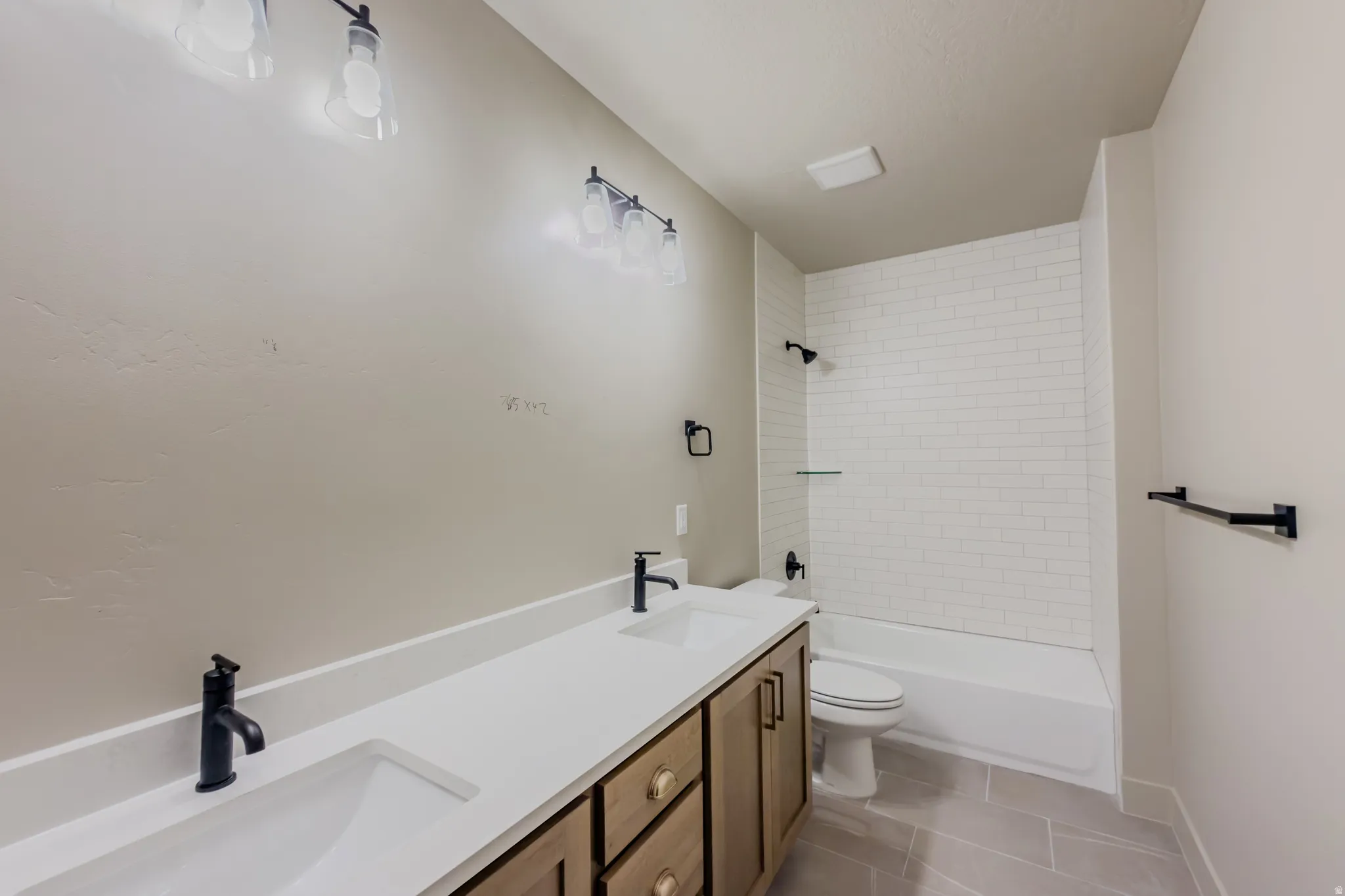 Full bath with double vanity, light tile patterned floors, and shower / tub combination