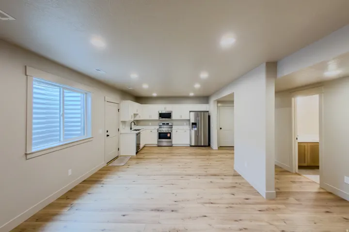 Kitchen featuring white cabinets, stainless steel appliances, light countertops, light wood-style floors, and recessed lighting
