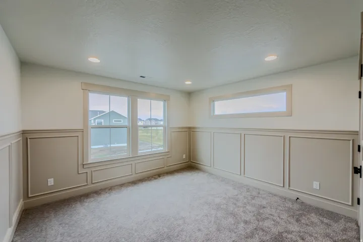 Spare room with wainscoting, a decorative wall, carpet floors, and a textured ceiling