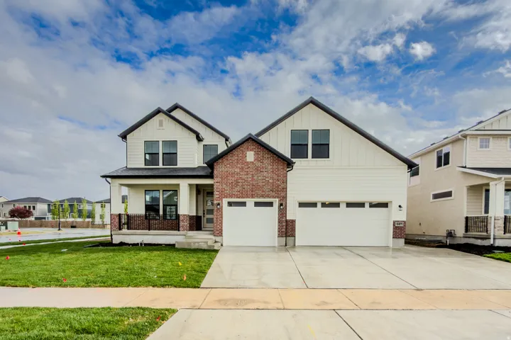 Craftsman inspired home featuring covered porch, board and batten siding, a garage, and driveway
