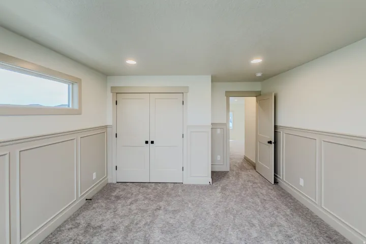 Unfurnished bedroom featuring a decorative wall, a wainscoted wall, a closet, recessed lighting, and light carpet