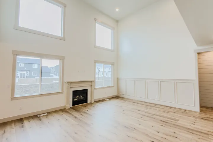 Unfurnished living room featuring a high ceiling, a fireplace, light wood-style flooring, recessed lighting, and a decorative wall
