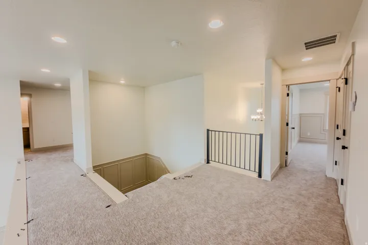 Corridor featuring light carpet, recessed lighting, a decorative wall, and an upstairs landing