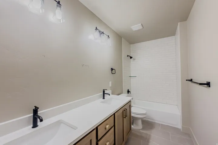 Full bath with double vanity, light tile patterned floors, and shower / tub combination