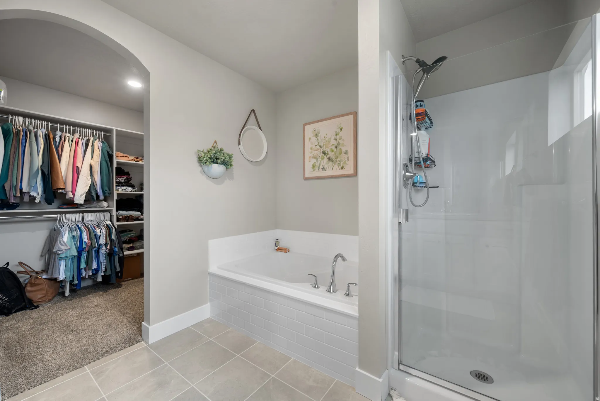 Full bath with a walk in closet, a shower stall, light tile patterned floors, and a garden tub