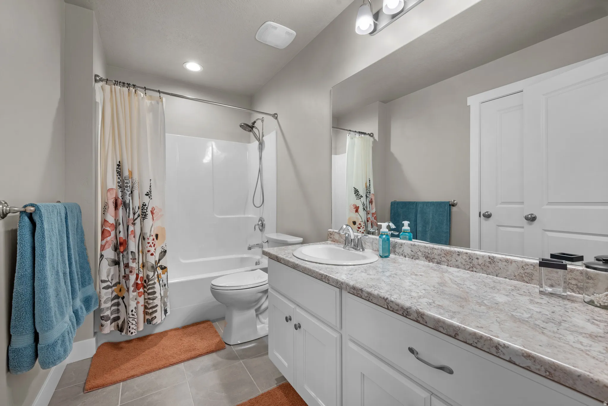 Bathroom with vanity, shower / bath combo, and light tile patterned floors