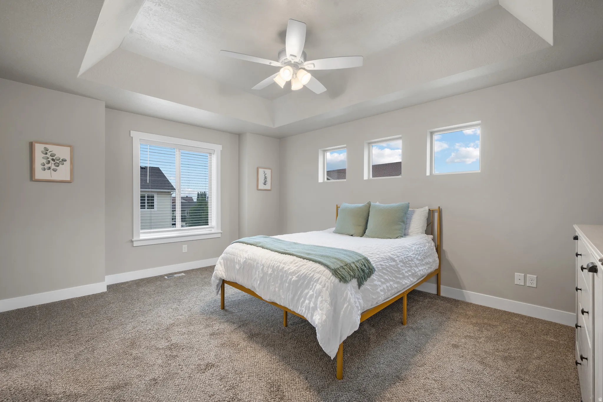 Bedroom featuring a tray ceiling, carpet flooring, and a ceiling fan
