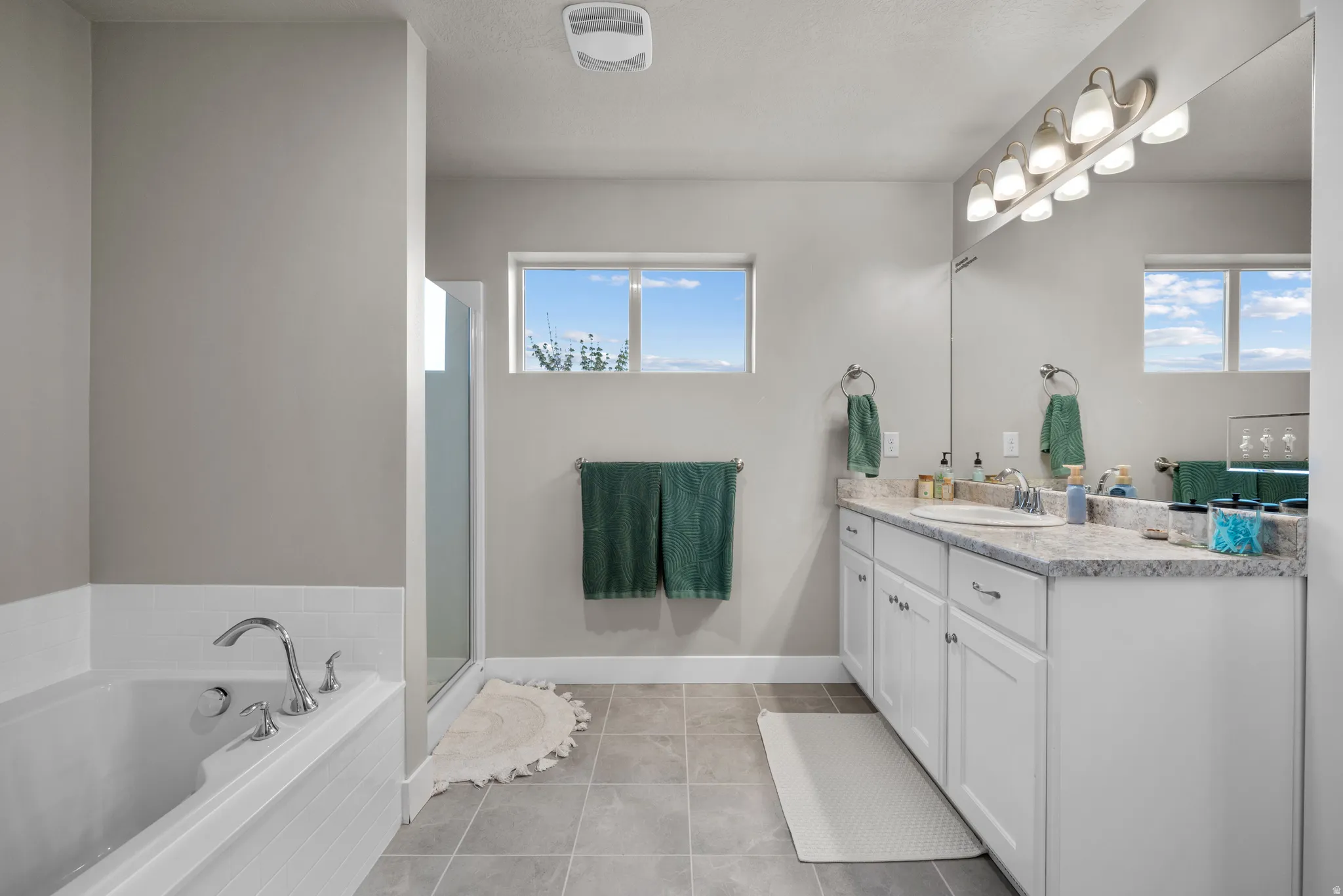 Full bath featuring vanity, a bath, a shower stall, and light tile patterned flooring