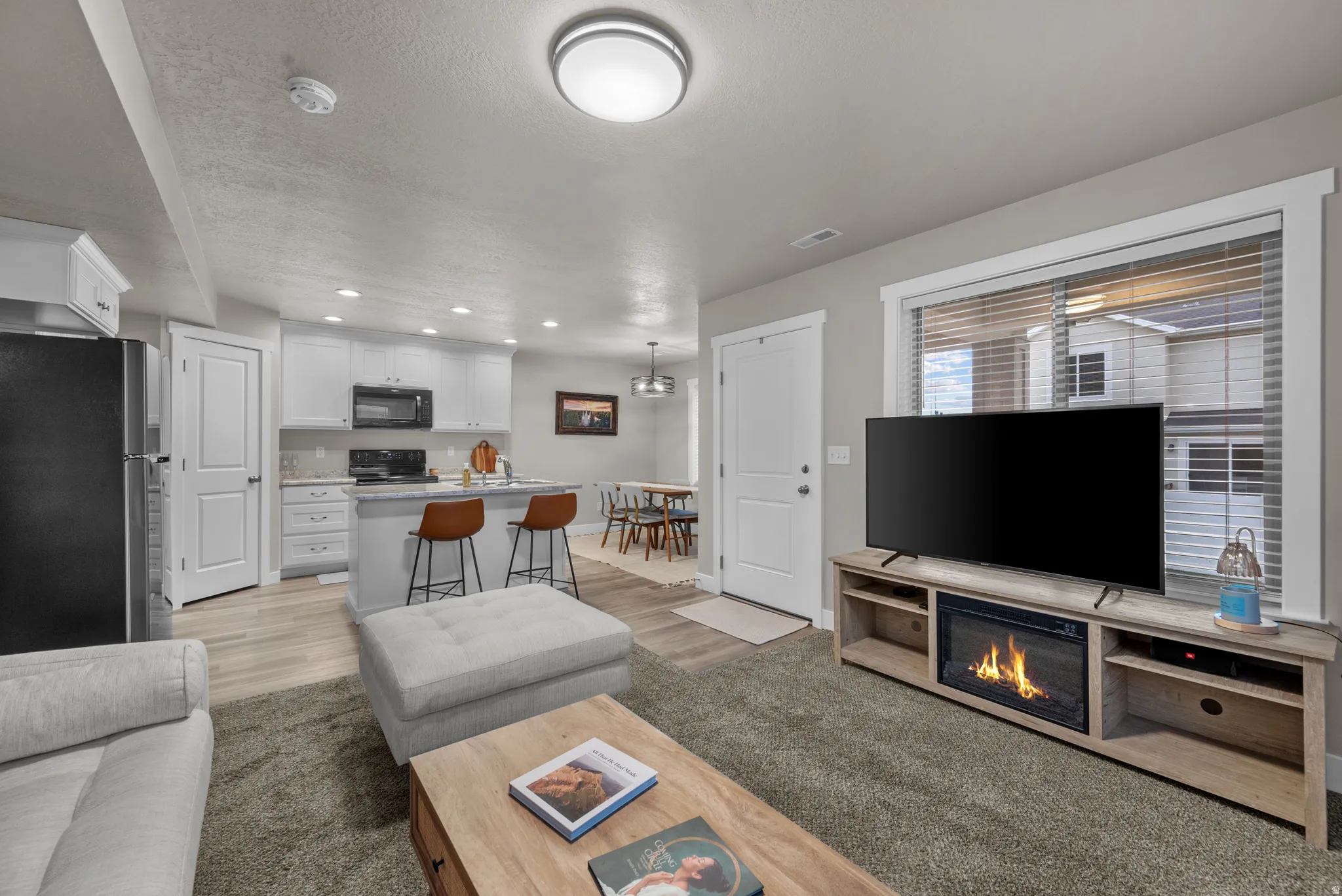 Living area with recessed lighting, light wood-type flooring, and a glass covered fireplace