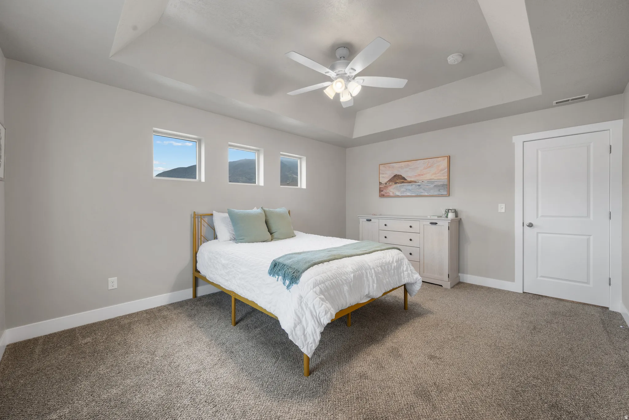 Bedroom with carpet flooring, a ceiling fan, and a tray ceiling