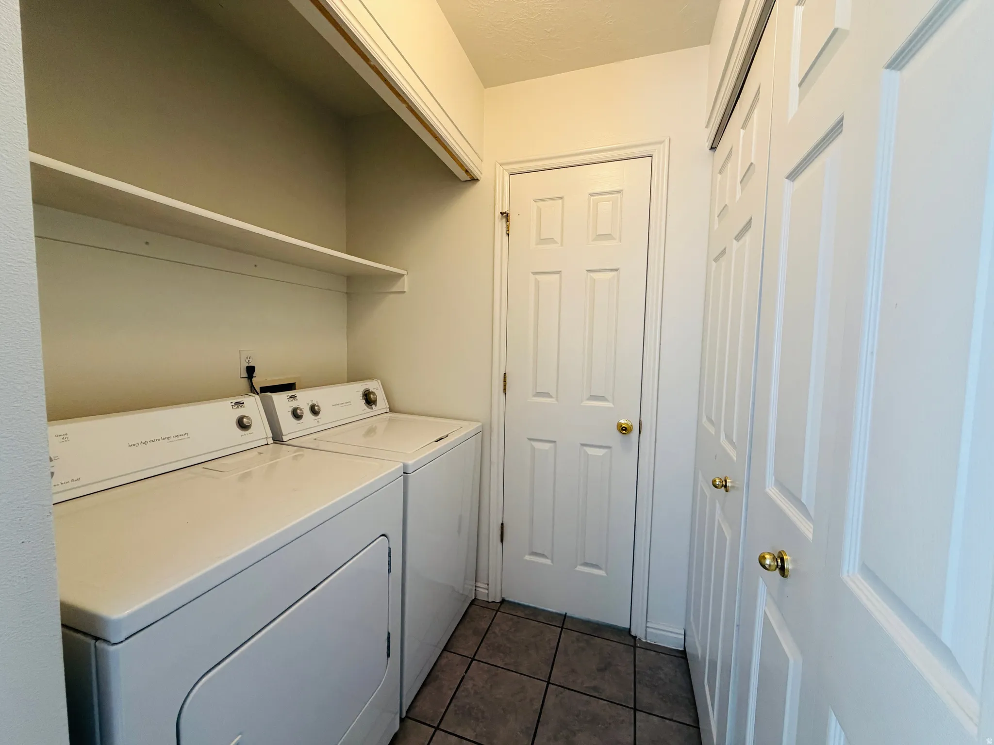 Laundry area featuring washer and dryer and dark tile patterned flooring