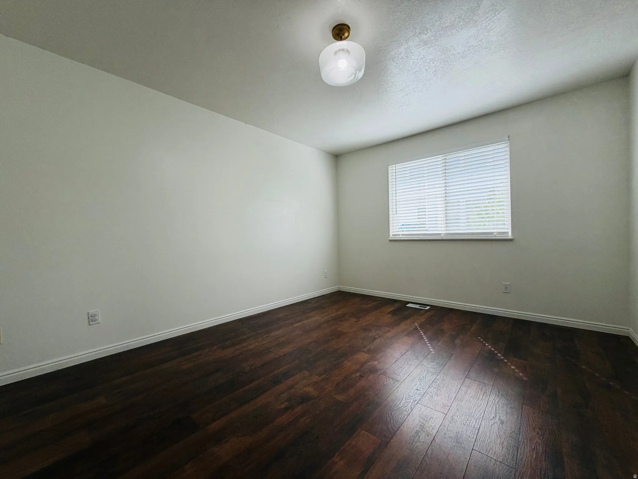 Spare room with dark wood finished floors and baseboards