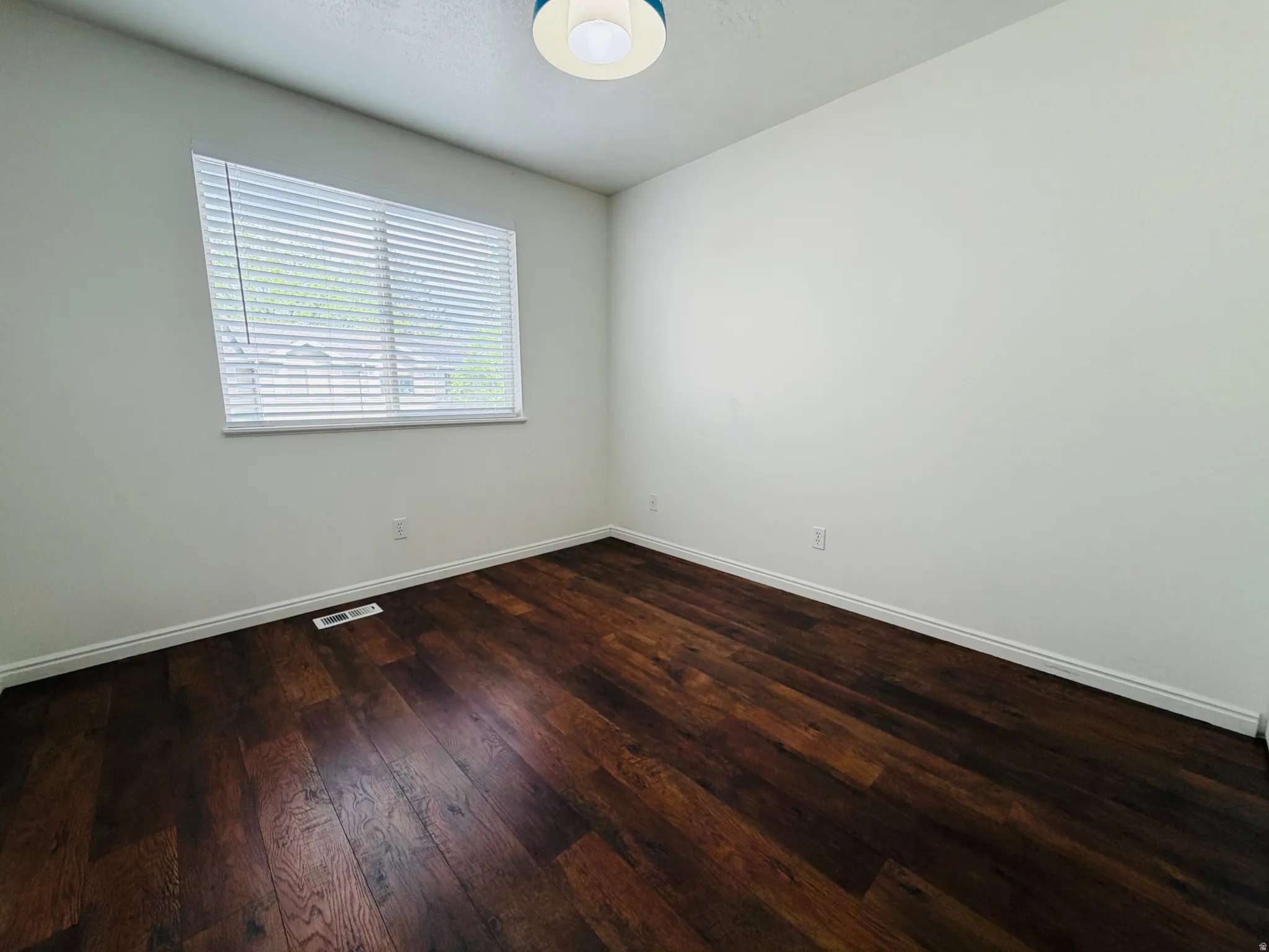 Empty room featuring dark wood finished floors and baseboards