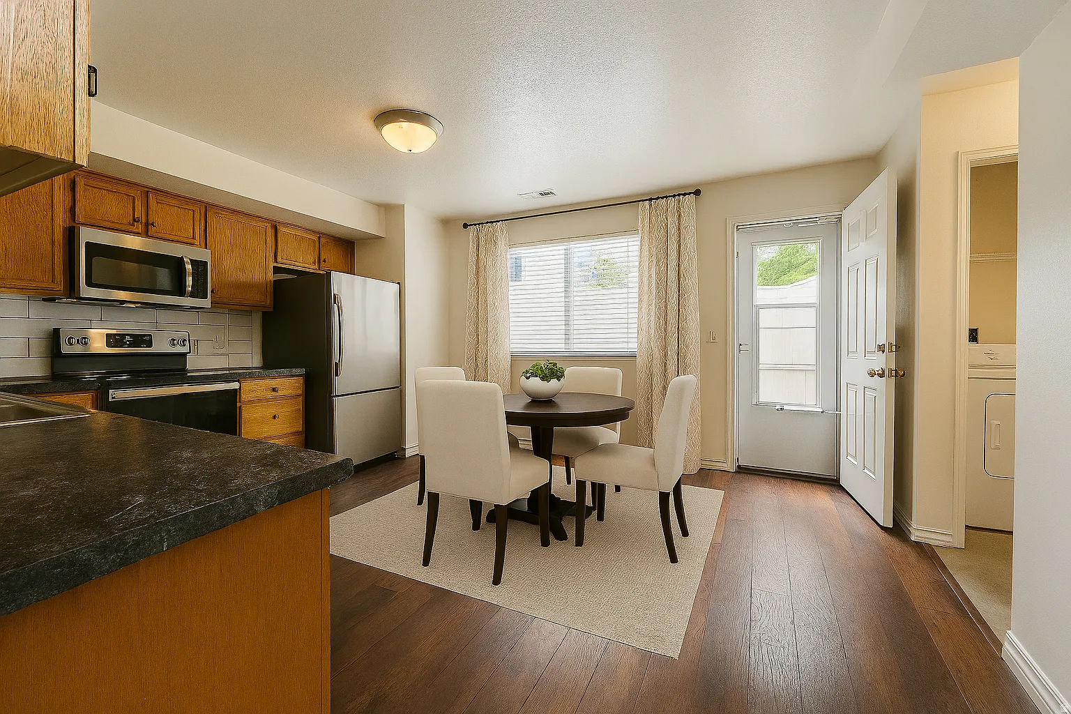 Kitchen featuring dark countertops, stainless steel appliances, wood finish cabinetry, dark wood-style flooring, and washer / clothes dryer