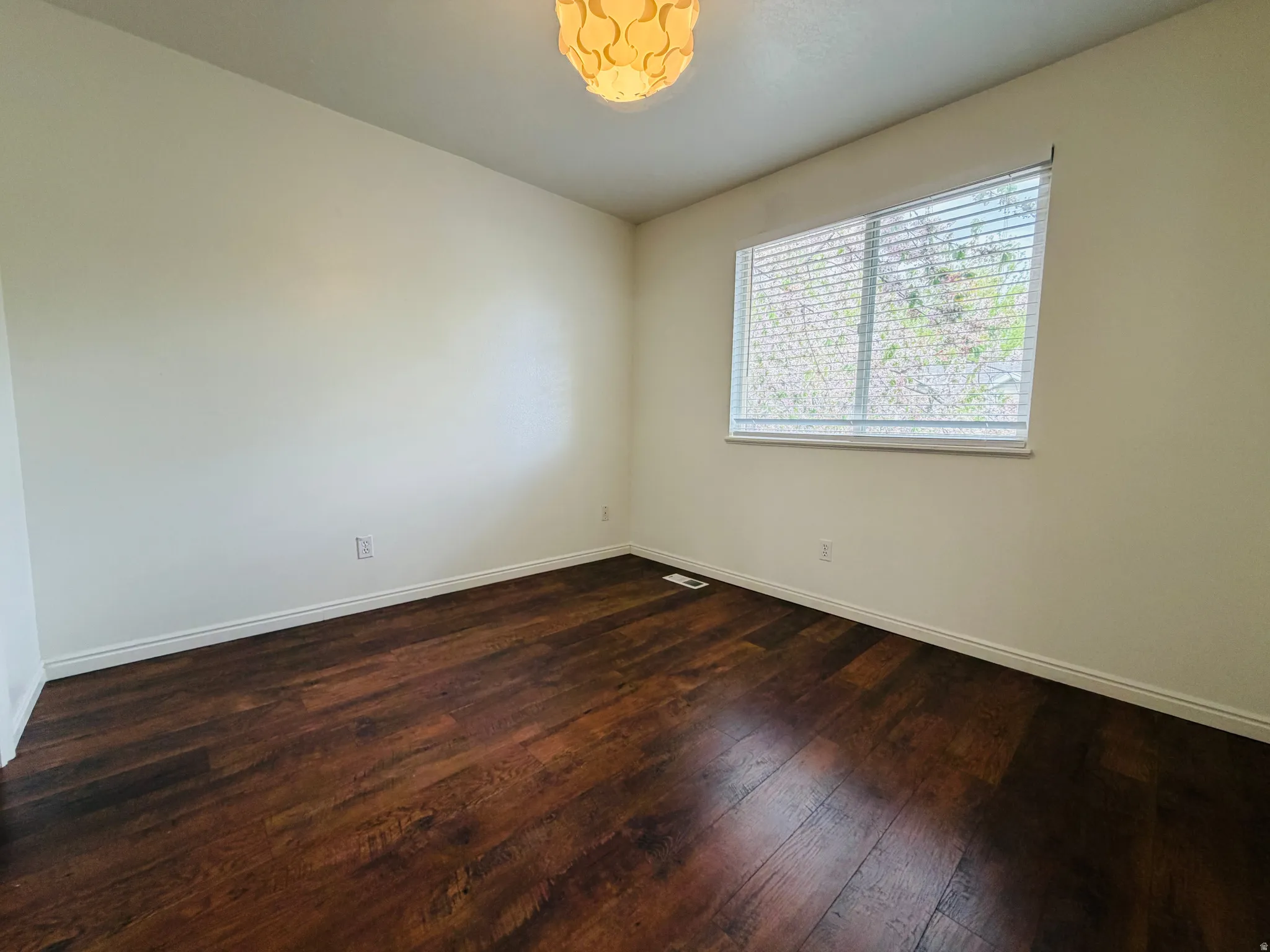 Empty room with dark wood-style flooring and baseboards