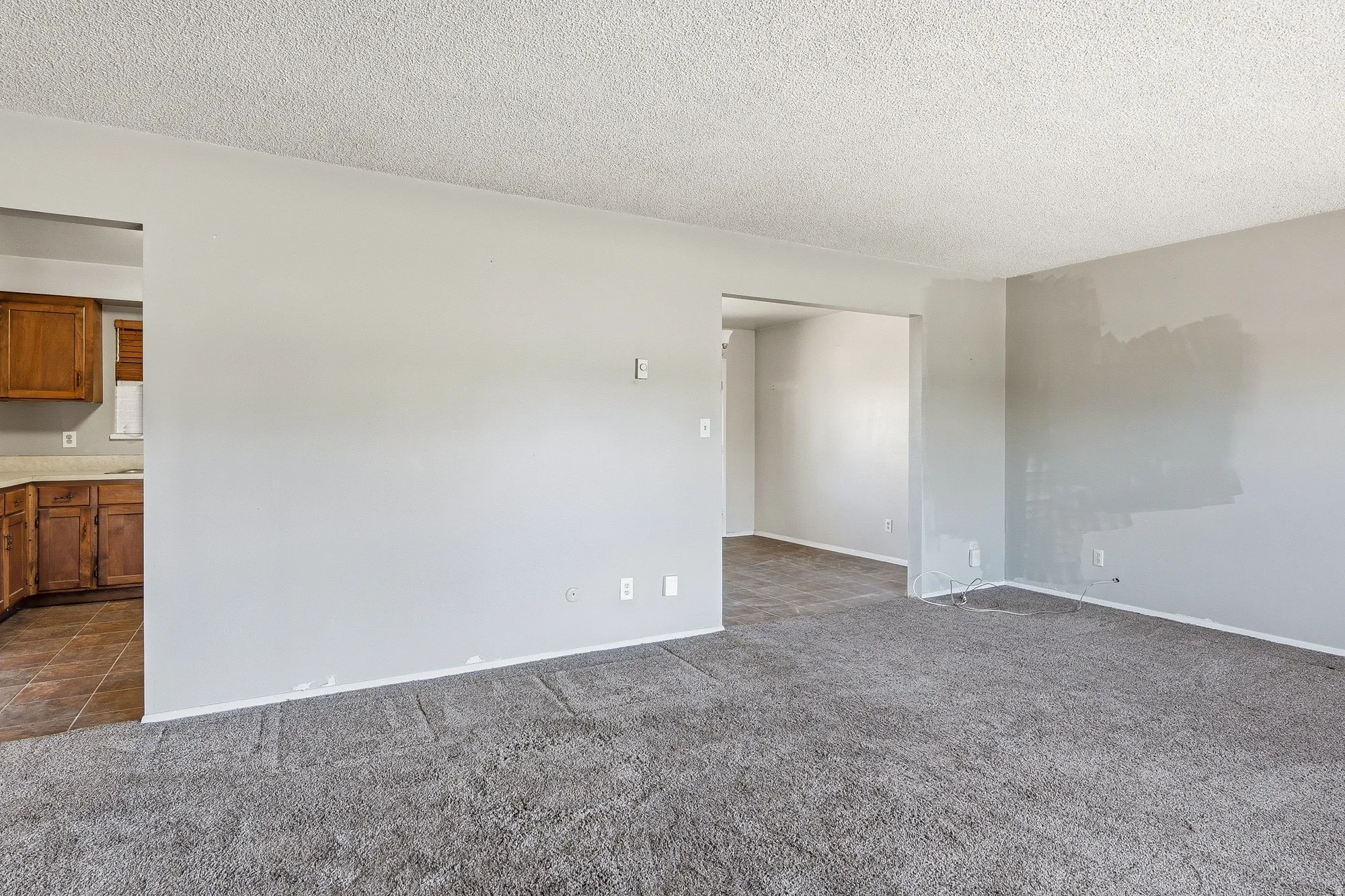 Unfurnished room featuring a textured ceiling and dark carpet