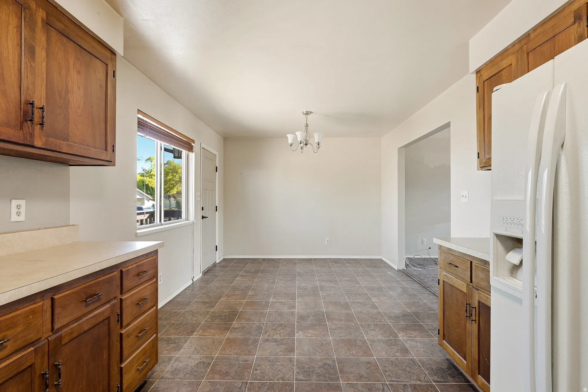 Unfurnished dining area with suspended lighting and stone finish floors